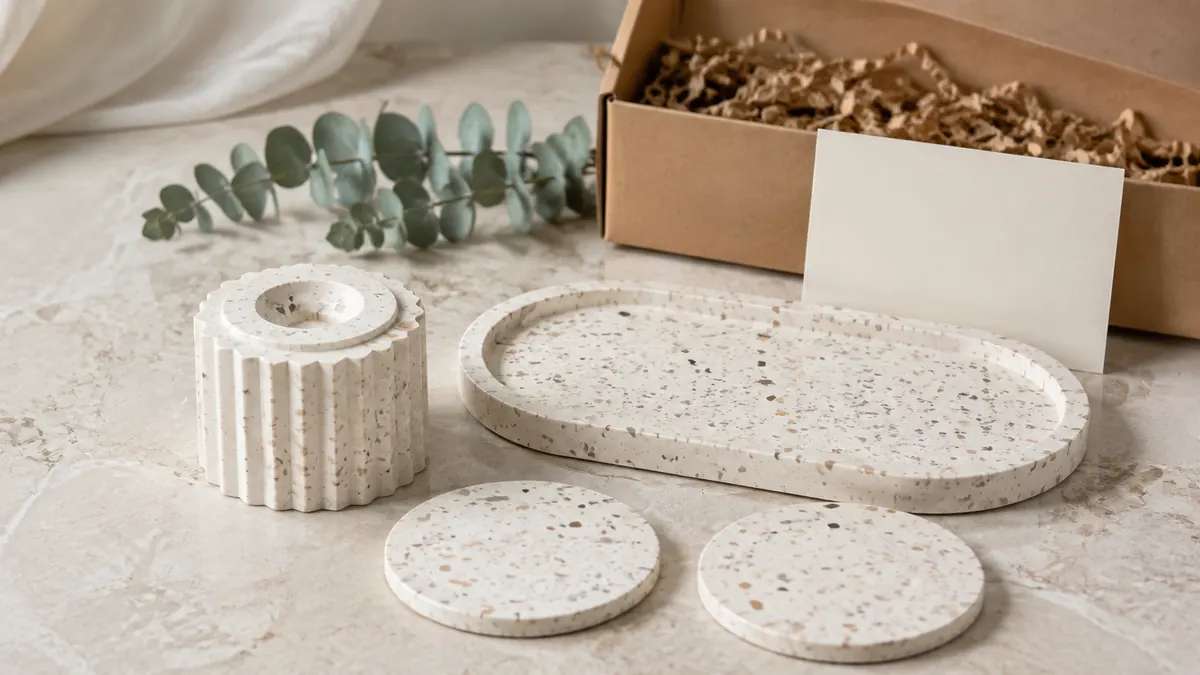 Colección de bandeja terrazzo, portavelas y posavasos junto a una caja de regalo